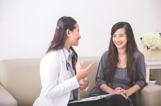 A female doctor is with a female patient.